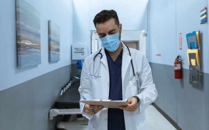 A healthcare professional reviewing medical charts in a hospital corridor, emphasizing safety and professionalism.